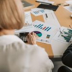 Profissionais analisam gráficos financeiros e usam calculadoras durante uma reunião de trabalho.