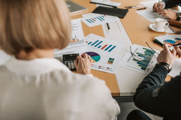 Profissionais analisam gráficos financeiros e usam calculadoras durante uma reunião de trabalho.